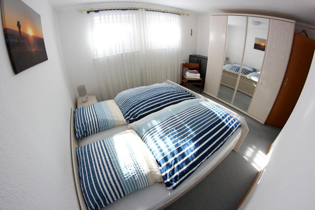 Schlafzimmer mit Blick zur Fensterfront und Spiegelschrank