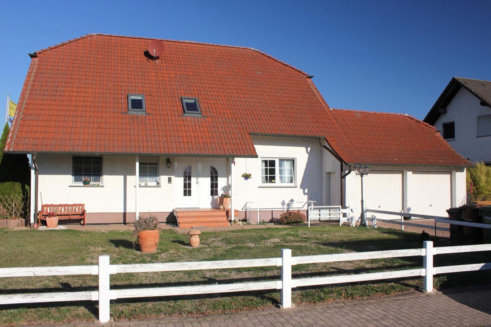 Außenansicht des Hauses mit rotem Ziegeldach und weißem Gartenzaun in Calden